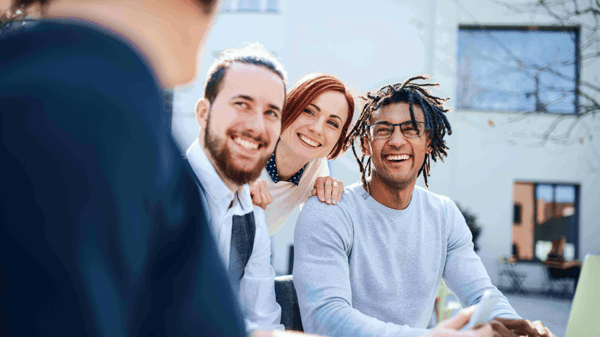 Three people smiling at a person.